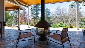 A covered patio with a stone floor, two wicker chairs, and a central fire pit.