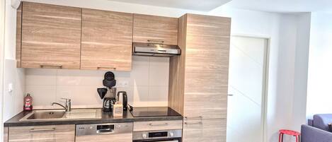 A modern kitchen with wooden cabinets, a built-in oven, and a coffee maker.