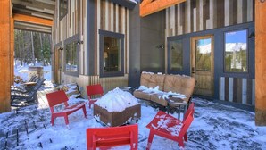 Un área de estar al aire libre con techo, con un sofá y sillas, rodeada de nieve.
