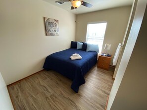 A bedroom with a bed, a ceiling fan, a window, and a motivational quote on the wall. - Custom Touch Village-Sulphur (Sulphur)