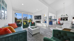 A spacious living room with a large window, a fireplace, and a view of a garden. - Access to Gym/Golf/Tennis/Pickleball via platinum membership. (Palm Desert)