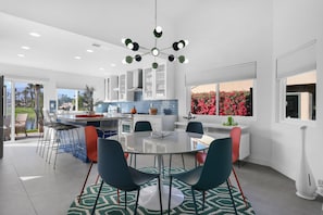 A modern kitchen with a round dining table, chairs, and a ceiling light fixture.