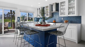 A modern kitchen with a central island, bar stools, and a view of a golf course. - Access to Gym/Golf/Tennis/Pickleball via platinum membership. (Palm Desert)