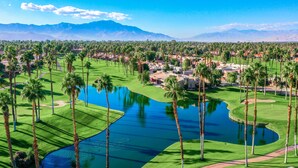 A golf course with a pond, palm trees, and a mountainous backdrop. - Access to Gym/Golf/Tennis/Pickleball via platinum membership. (Palm Desert)