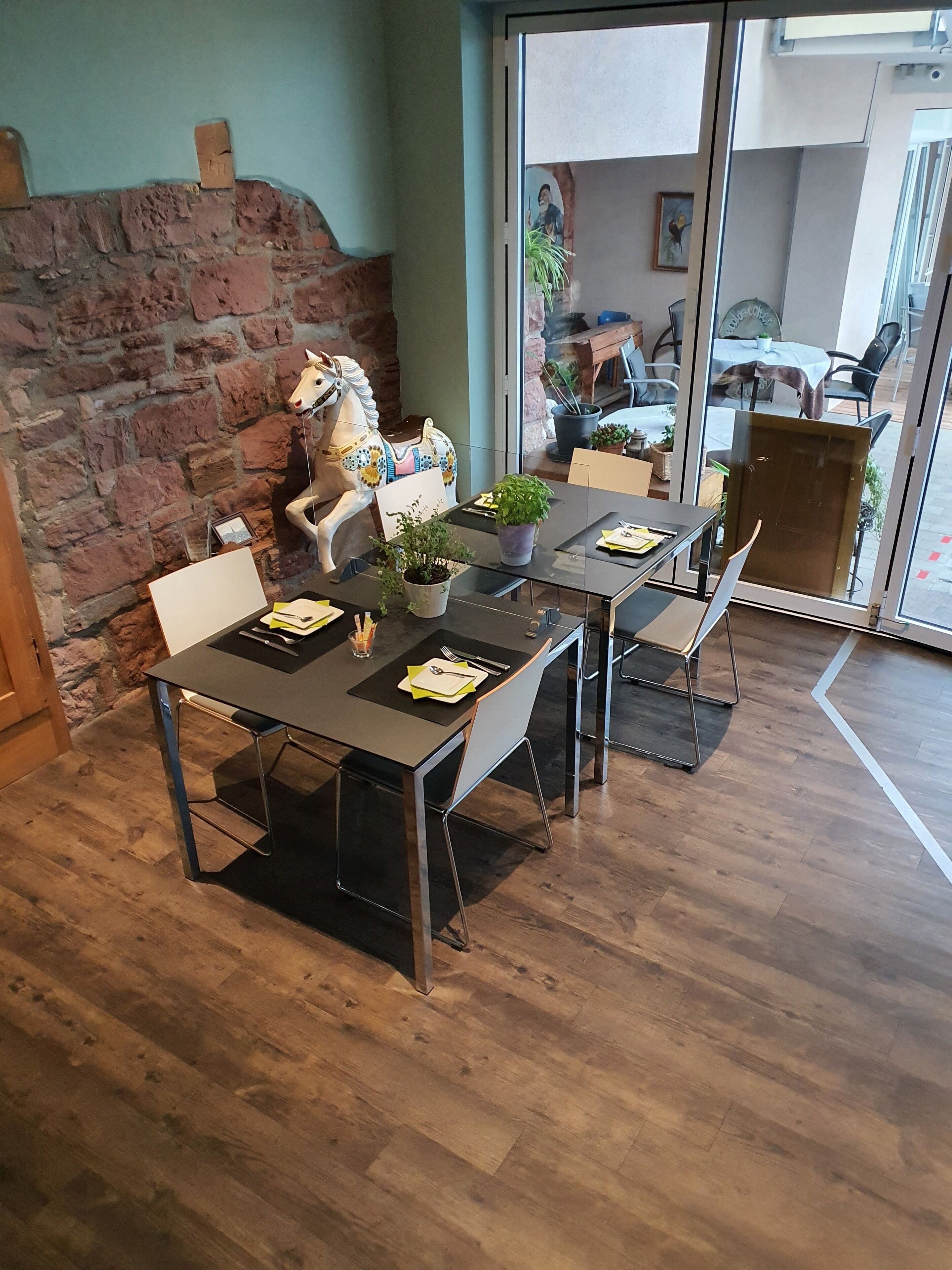 A dining area with a brick wall, a white horse sculpture, and a glass door leading outside.