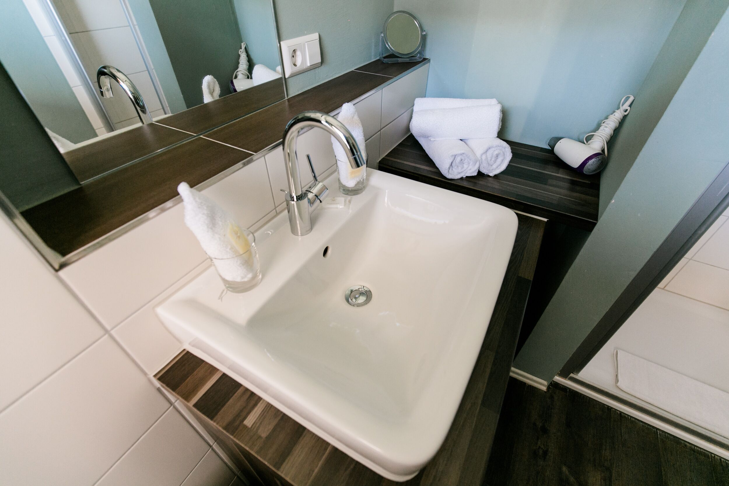 A modern bathroom with a white sink, a mirror, and a towel rack.