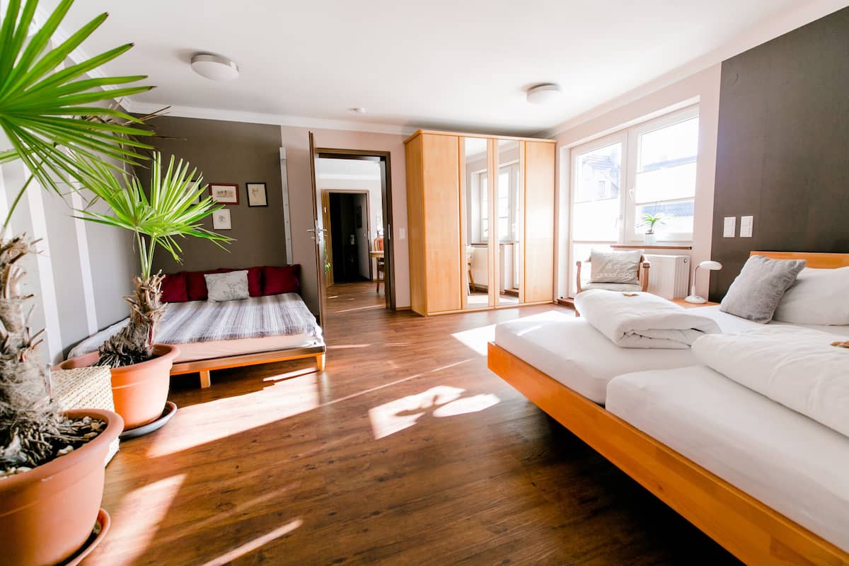 A modern bedroom with a wooden bed, a bench, and a potted plant.