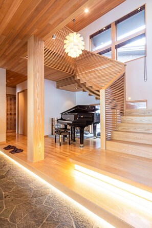 A spacious room with a grand piano, wooden slatted ceiling, and a stone-tiled floor. - 4BedroomLocated in the center of Hirafu a luxurious large chalet / Abuta-gun Hokkaidō (Abuta-gun)