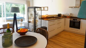 Une cuisine moderne avec un coin repas, comprenant un meuble vitré, un four encastré et une vue sur l’extérieur.