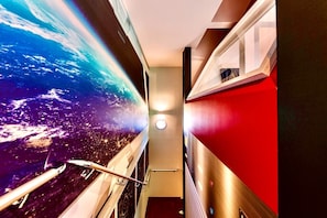 Stunning Earth-inspired mural sets the tone for a modern corridor leading to a staircase with a bold accent wall.