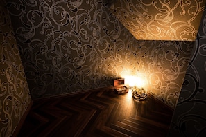 Cozy retreat with a herringbone-patterned floor, ornate wallpaper, and a vintage wooden chest.