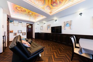 A spacious living area with a large sofa, a dining table, and a flat-screen TV.