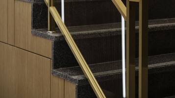 A staircase with a golden handrail and dark granite steps.