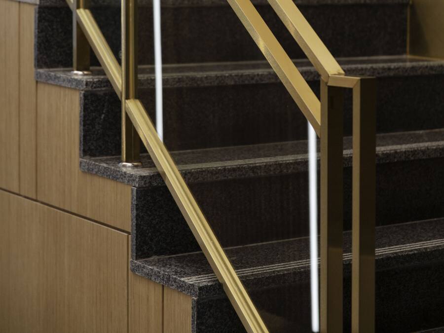 A staircase with a golden handrail and dark granite steps.