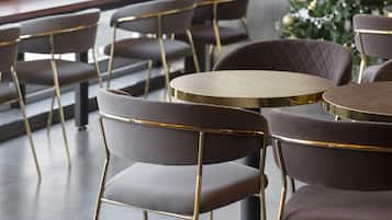 Un espace de restauration moderne avec des tables et des chaises rondes, un sapin de Noël et une vue sur la ville grâce à de grandes fenêtres.