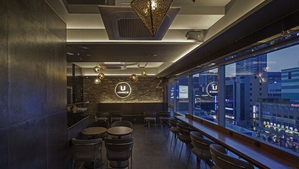 Un área de estar moderna con bar, asientos y vista a la ciudad.
