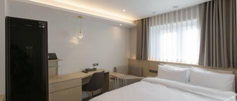 A hotel room with a bed, a desk, a chair, a wardrobe, and a window with curtains.
