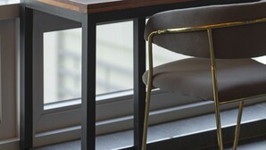 Un escritorio moderno con una silla, ubicado cerca de una ventana que ofrece vistas de un edificio.