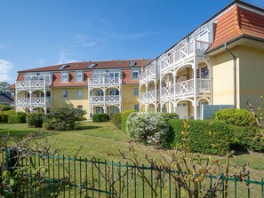 A multi-story building with balconies and a garden area.