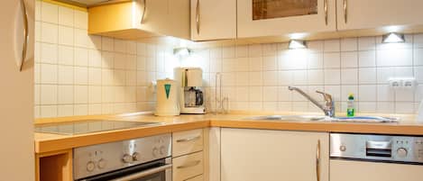 A modern kitchen with white cabinets, a built-in oven, a coffee maker, and a sink with a faucet.