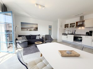 En moderne stue med sofa, spisebord og et køkkenområde.