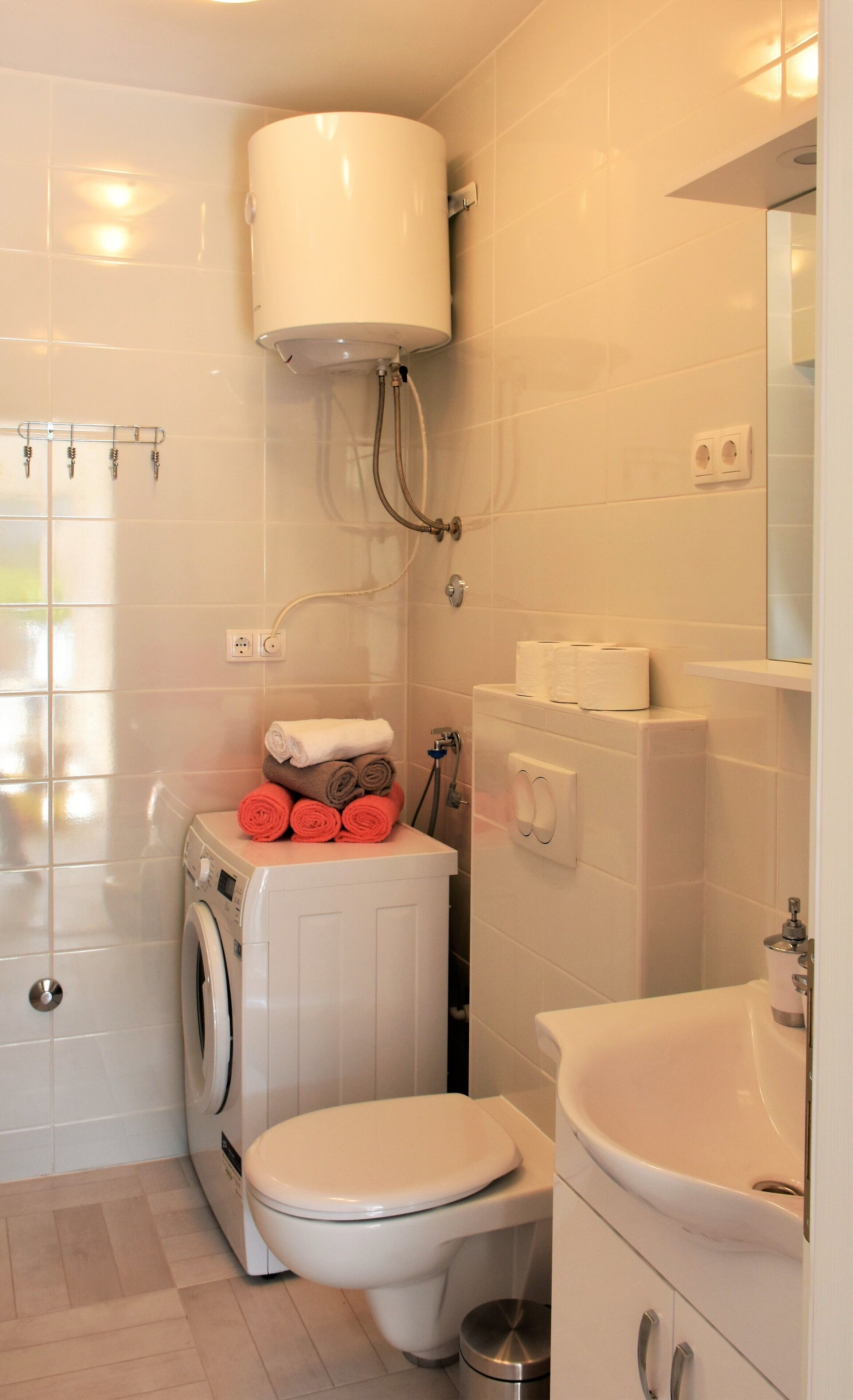 Ein kleines Badezimmer mit Waschmaschine, Toilette und Waschbecken.