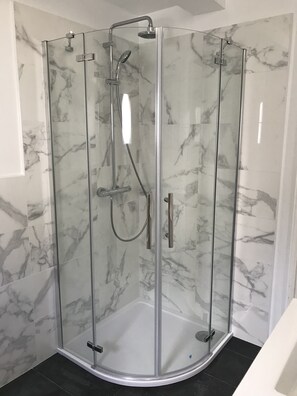 Een bad/douchecombinatie, een bubbelbad, een haardroger, handdoeken
