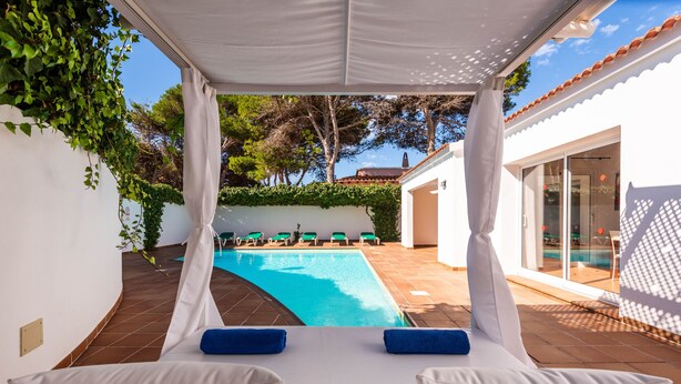 Un espace aménagé au bord de la piscine, avec des chaises longues, une piscine et un coin salon abrité.