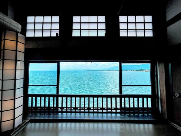 Enjoy a serene view of the water and distant land from the room's large window with a balcony.