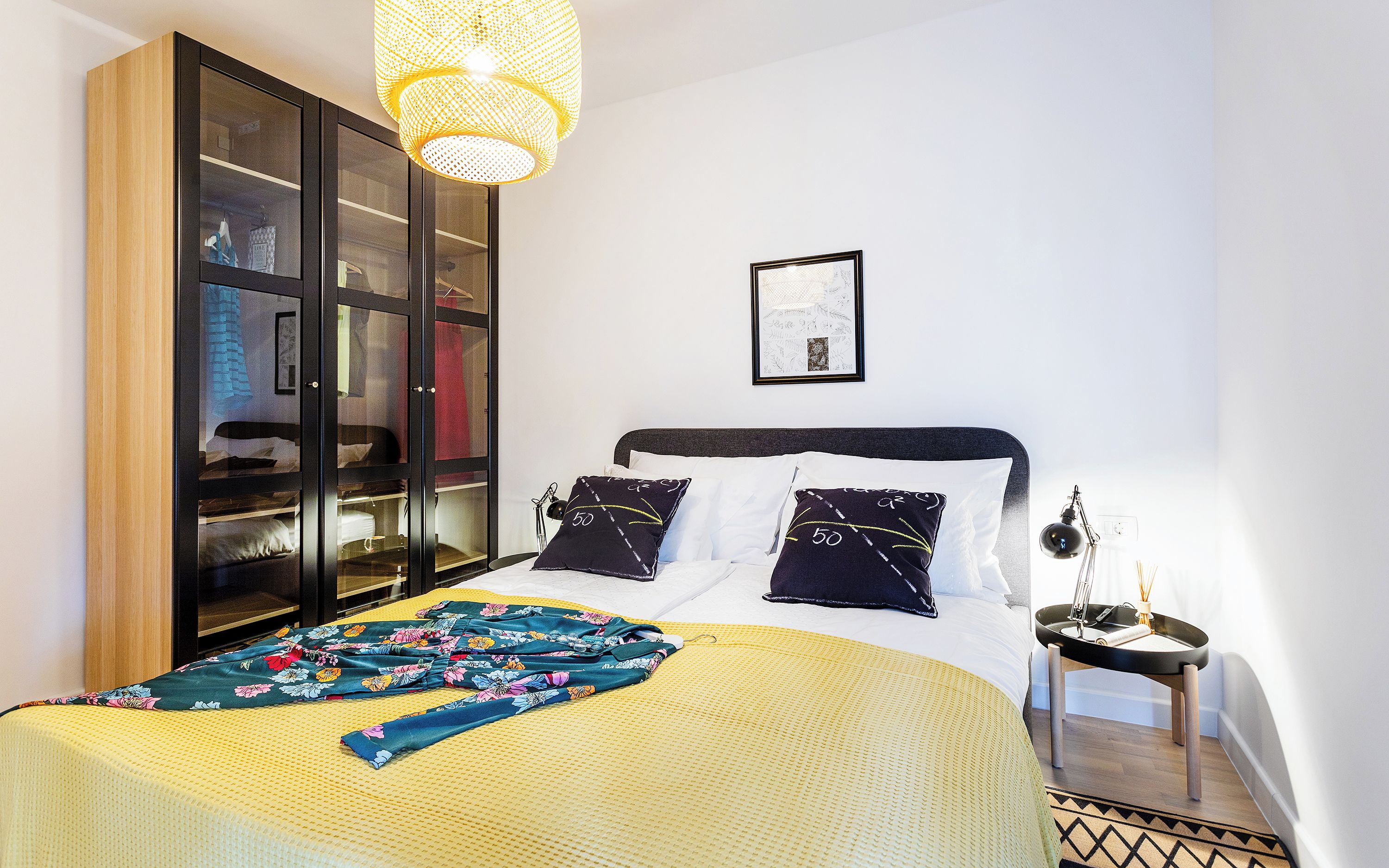 Une chambre à coucher comprenant un lit, une table de chevet, une lampe, une armoire et un luminaire suspendu.