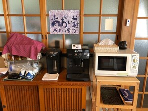 Compact kitchenette with coffee maker, kettle, microwave, and teapot.