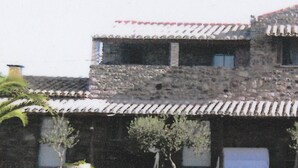 A stone building with a tiled roof, multiple windows, and a balcony. - DOMUSANTIGA - Love nest (studio flat) a few minutes from the sea (San Giovanni Suergiu)