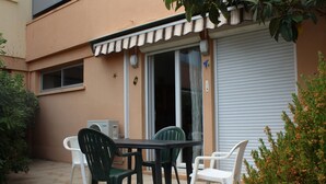 Un patio al aire libre con una mesa, sillas, un ventanal corredero y un toldo blanco.