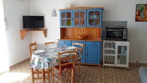 Una cocina compacta con una mesa de comedor, sillas, un microondas y un televisor.