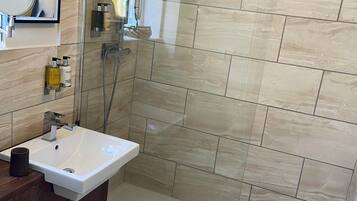 A modern bathroom with a glass-enclosed shower, a white sink, and a wooden vanity.