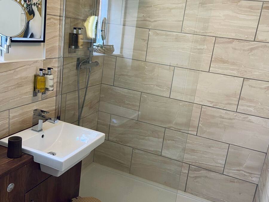 A modern bathroom with a glass-enclosed shower, a white sink, and a wooden vanity.