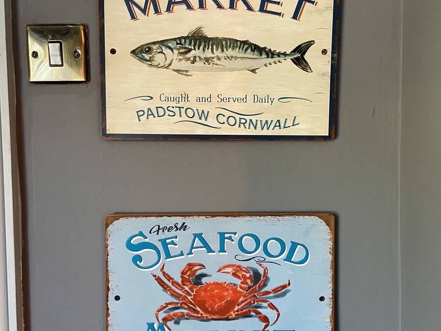 Two signs on a wall: one for a fresh fish market and another for a seafood market.