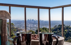 Un balcon avec deux tasses en métal, une vue sur la ville et un ciel dégagé.