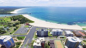 A coastal cityscape with a beachfront, high-rise buildings, and a parking area. - Ebbtide 2 - On Main Beach! (Forster)