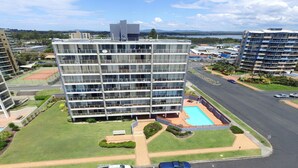 A multi-story hotel with a rooftop pool, surrounded by well-maintained lawns and a tennis court. - Ebbtide 2 - On Main Beach! (Forster)