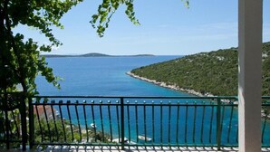 Un balcon donnant sur une mer turquoise et une côte rocheuse.