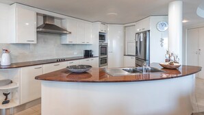 Una cocina moderna con armarios blancos, encimera de granito, electrodomésticos de acero inoxidable y horno empotrado.
