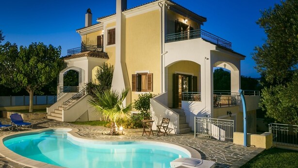 Una casa de dos pisos con piscina, mobiliario exterior y una escalera que conduce a un balcón.
