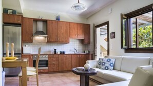 Cocina compacta con armarios de madera, horno integrado y comedor con mesa y sillas.