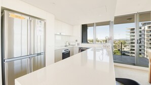 Una cocina moderna con una isla grande, electrodomésticos de acero inoxidable y vistas a una zona residencial.