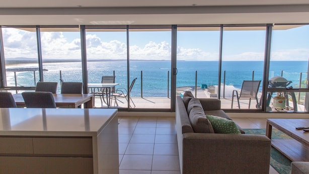 A modern room with a large sliding glass door leading to a balcony with a sea view. - Strand Beachside 903 (Forster)