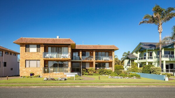 Un immeuble de deux étages avec une façade en briques, de grandes fenêtres et un balcon.