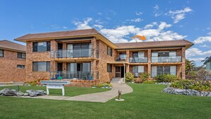 A two-story brick building with balconies, a sign for 'Surf Spray', and a well-maintained lawn.
