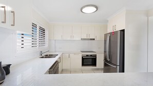 A modern kitchen with white cabinetry, stainless steel appliances, and a built-in oven.