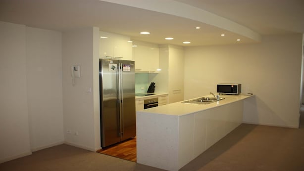 A modern kitchen with a stainless steel refrigerator, a microwave, and a sink. - The Reef 103 - Lakeside! (Forster)